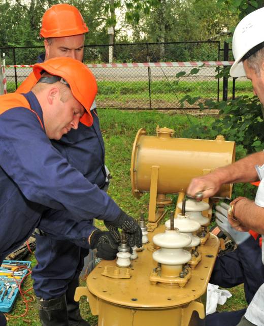 A team of electricians is making repairs three phase electric power oil  transformer